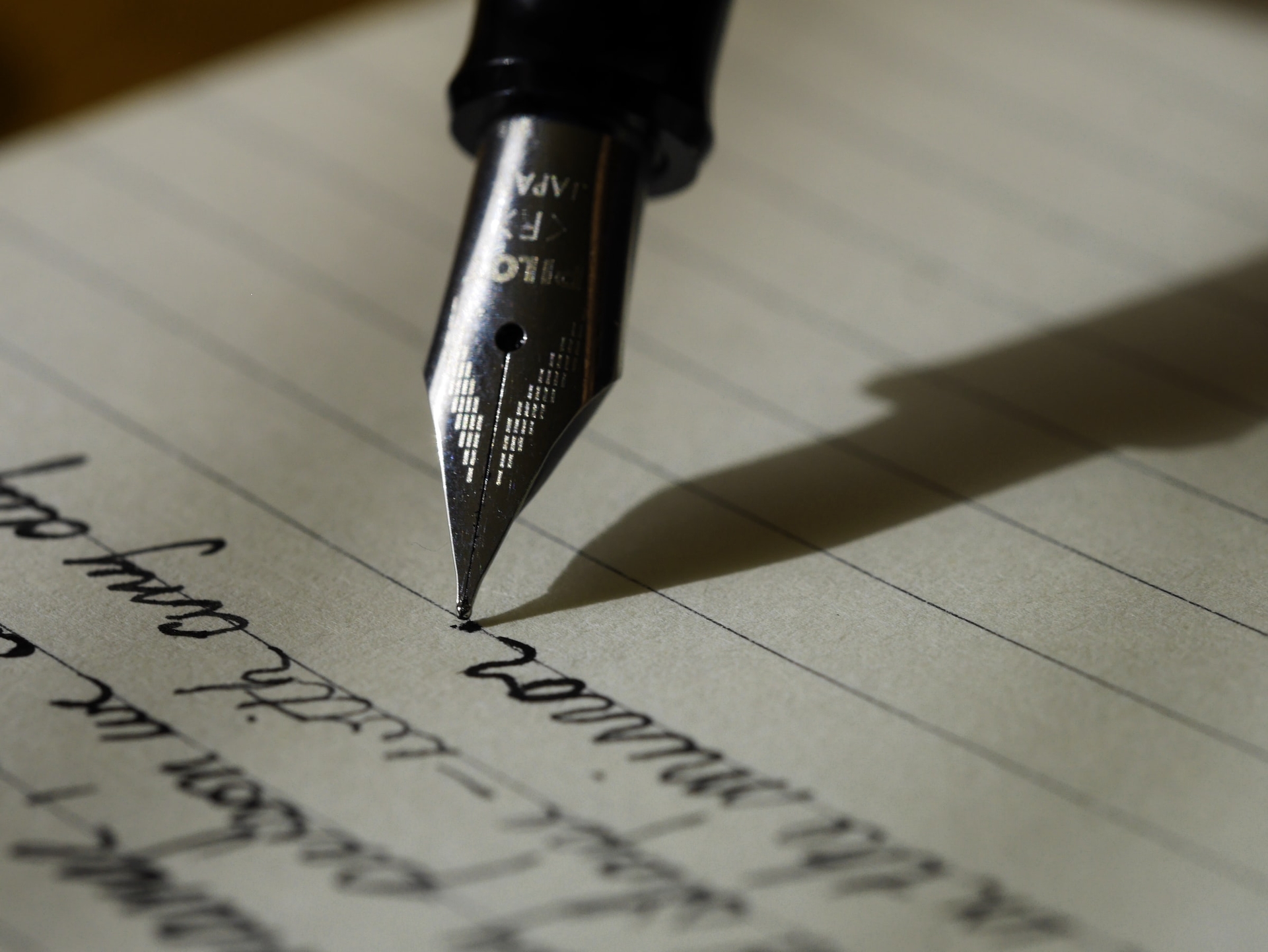 Writing with a fountain pen - Photo by Aaron Burden on Unsplash (unsplash.com/@aaronburden)