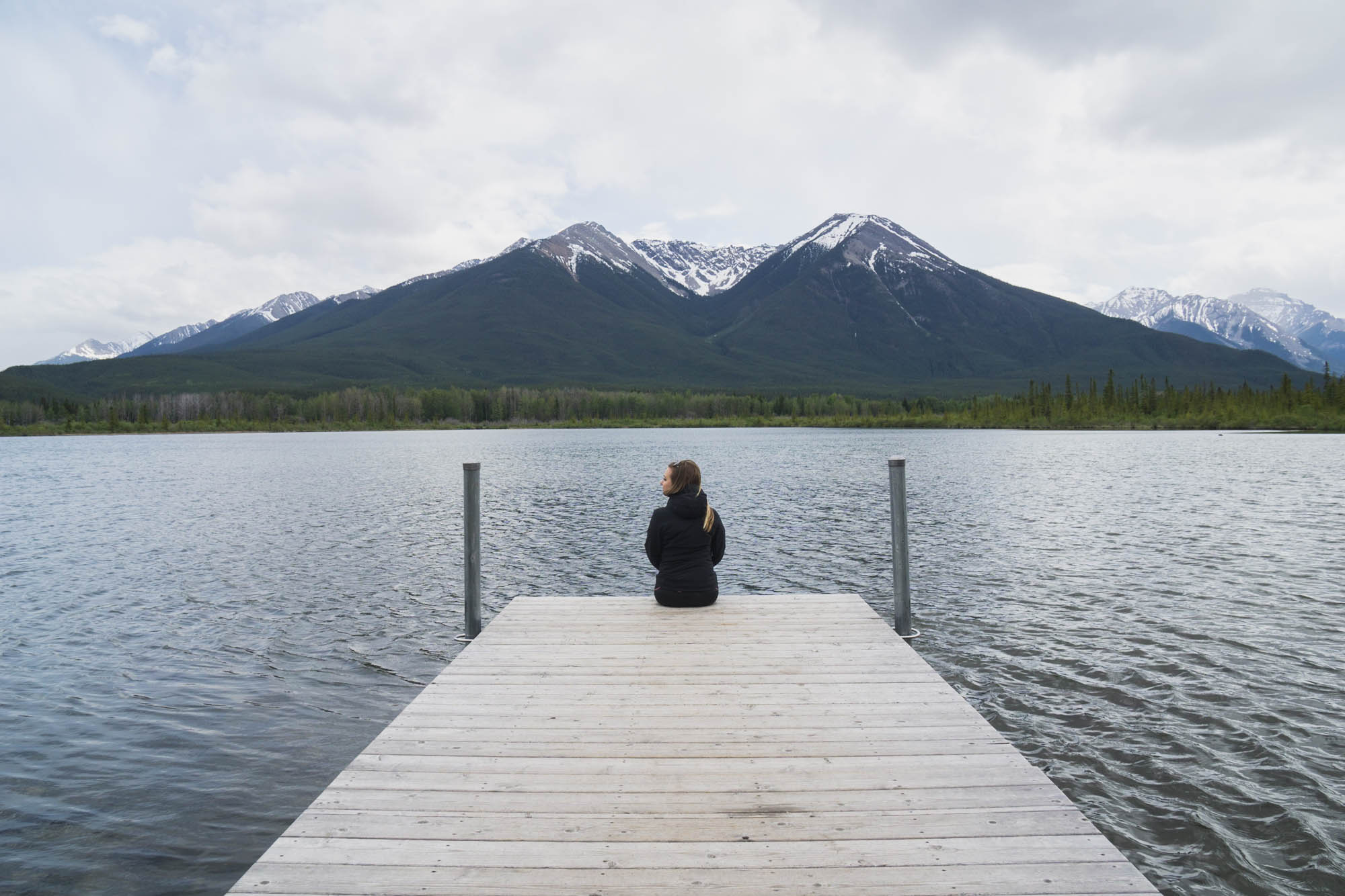 Jami sitting at the end of a dock at Vermillion Lakes located within Banff National Park in Alberta, Canada